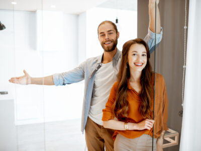 Portrait of a young couple standing together at the new modern studio. Concept of happy real estate owners
