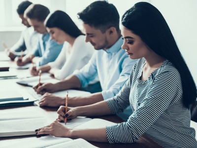 Young People Studying in Classroom at College. Education Concept. Writing on Lesson. Multiethnic Students. Sitting at Desk. Studying Together. Writing Notes with Pen. Learning in College.